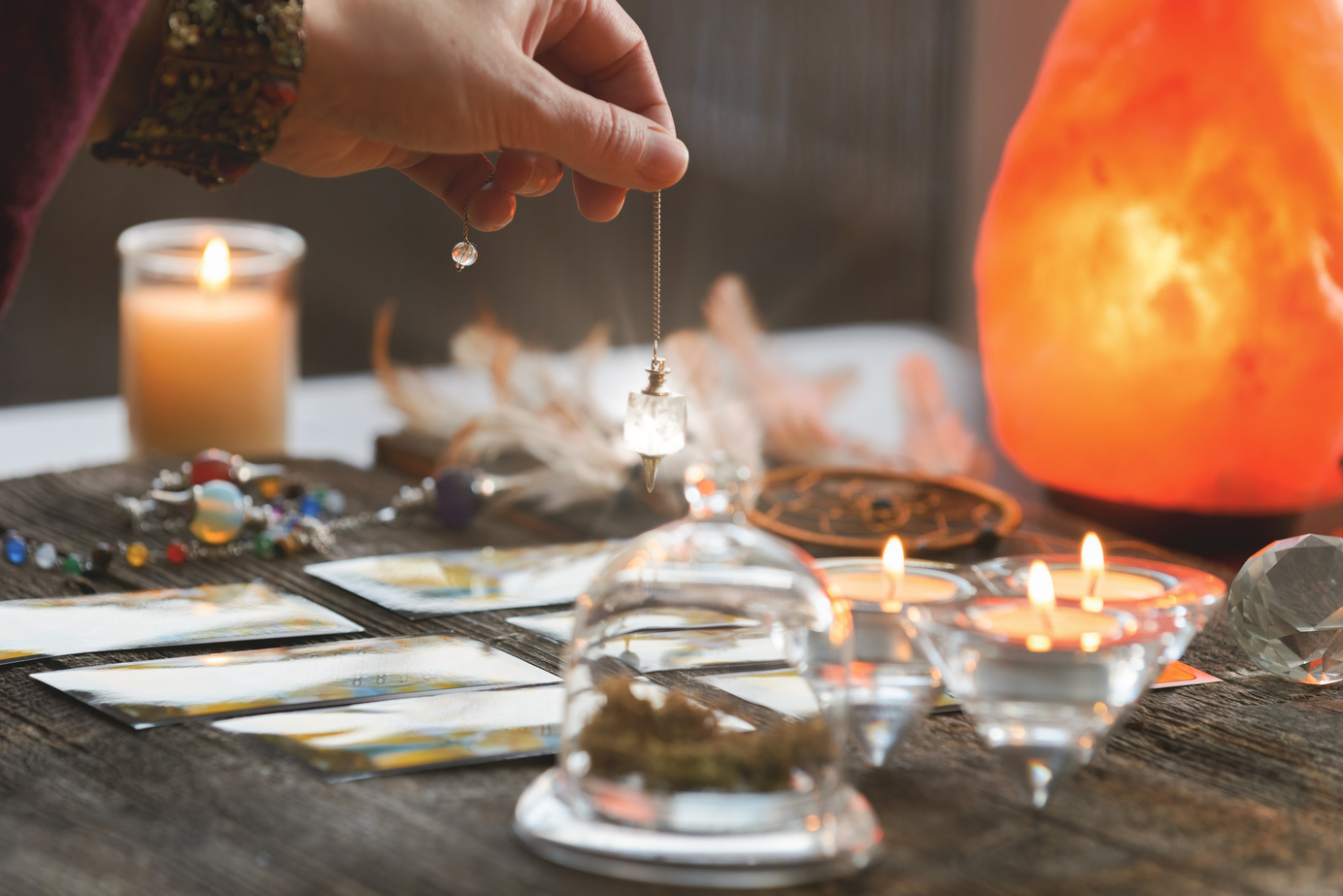 Hand with pendulum over tarot cards